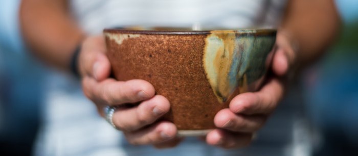 a woman's hands holding out a handmade bowl