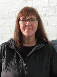 YWC Director of Client Services, Darlene Smith-Harrison standing in front of a light coloured brick wall