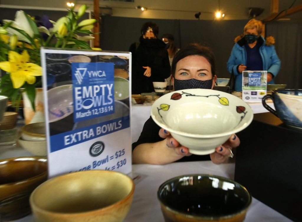 a woman wearing a mask holding a ceramic bowl at the 2021 YWCA Empty Bowls event