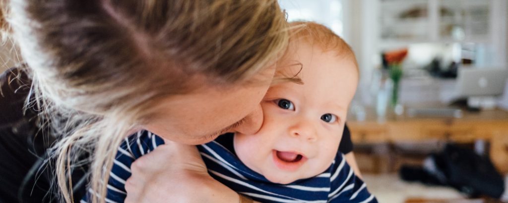 Image of a young mother kissing her cute baby on the cheek
